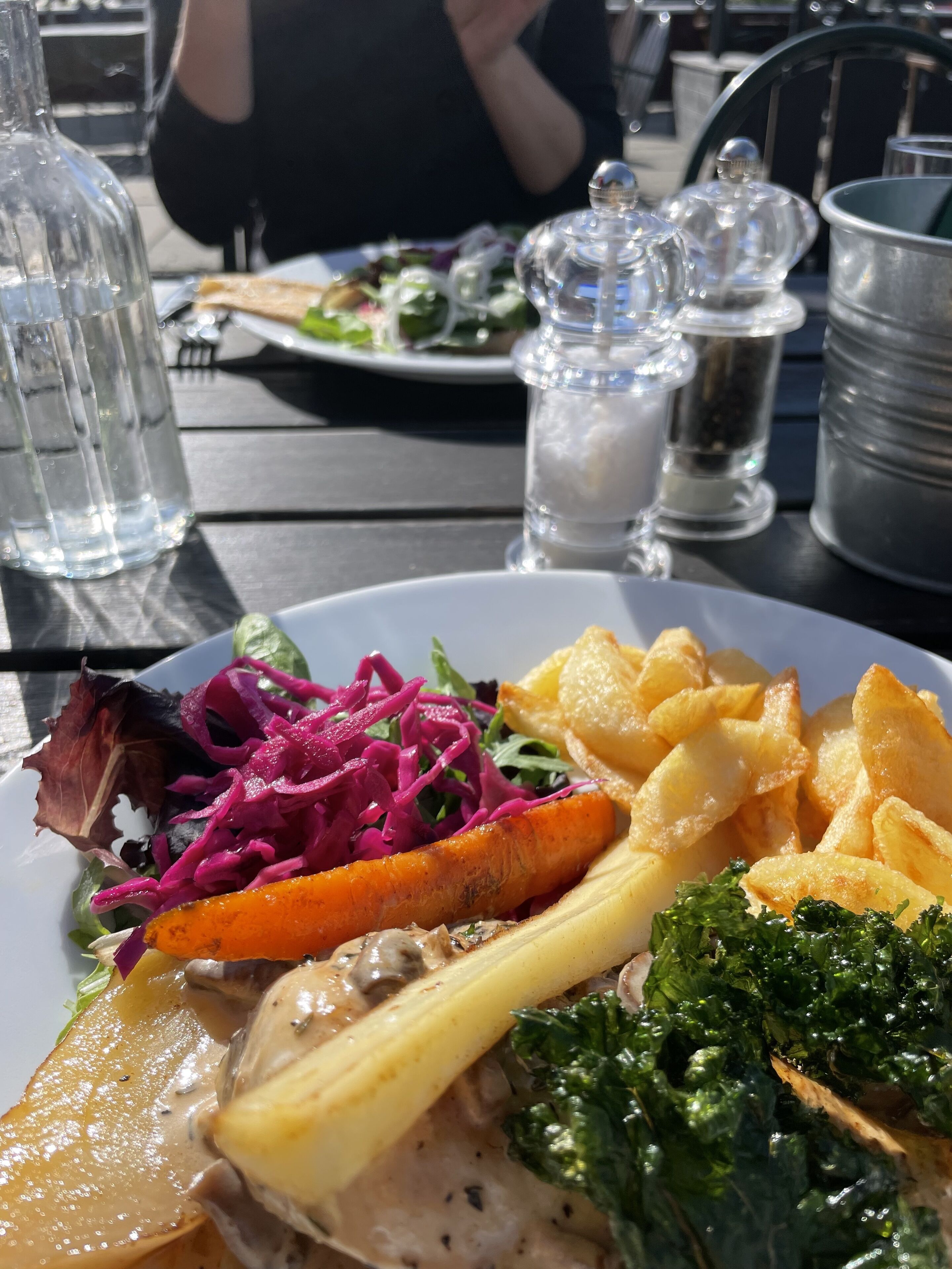 Una mesa de comedor con un plato de comida, que incluye una ensalada, verduras asadas y un trozo de carne.
