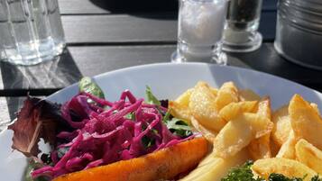 Una mesa de comedor con un plato de comida, que incluye una ensalada, verduras asadas y un trozo de carne.