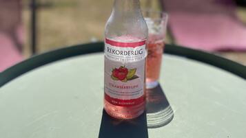 A bottle of Rekorderlig Premium Swedish Cider on a table with a glass of pink drink beside it.