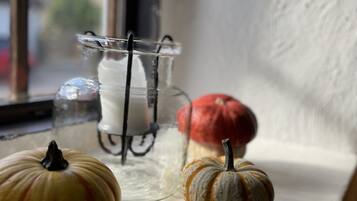 A window sill with two small pumpkins and a glass vase with a candle.