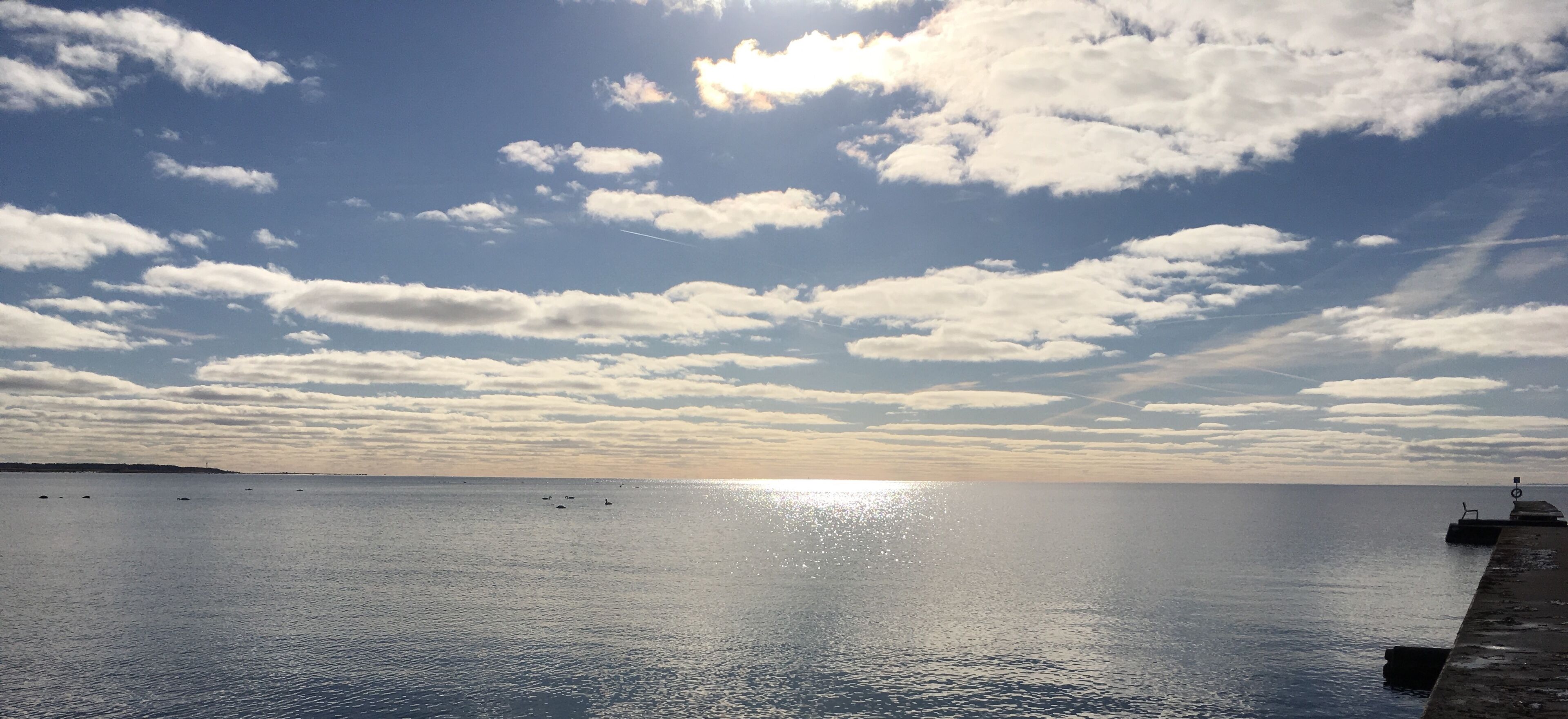 Une mer calme, un ciel dégagé et quelques nuages.
