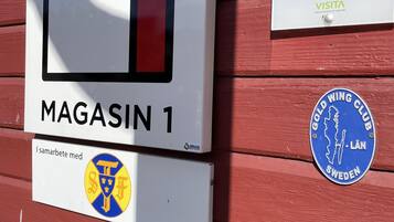 Une enseigne pour le « Magasin 1 », avec un logo, une enseigne indiquant « HÔTEL » et un badge du « Gold Wing Club ».