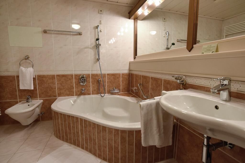 Un baño con bañera, dos lavamanos y un bidé.