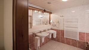 A bathroom with two sinks, a large mirror, and a towel rack. - Reduce Hotel Thermal (Bad Tatzmannsdorf)