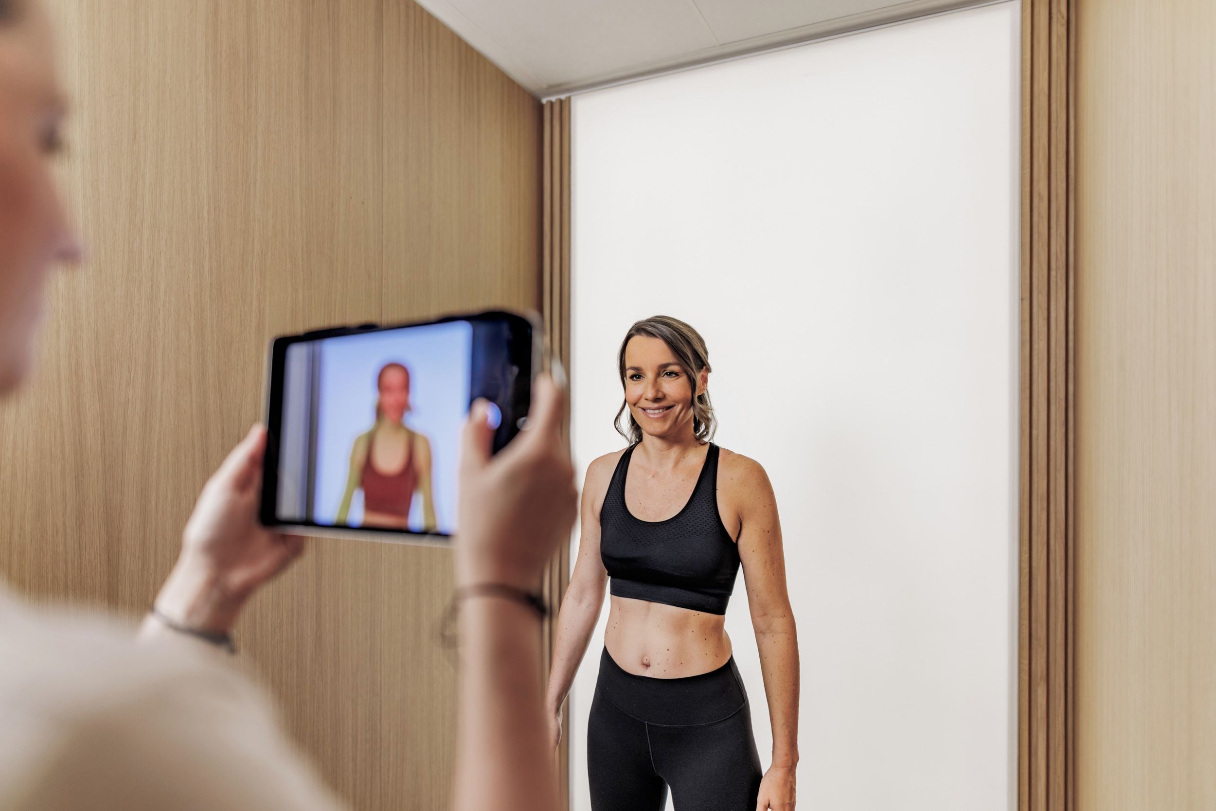 Une personne utilise un téléphone intelligent pour prendre une photo d’elle-même dans une pièce aux murs en bois et à la porte blanche sobre.