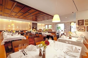 A restaurant with multiple dining tables, chairs, and a variety of table settings.