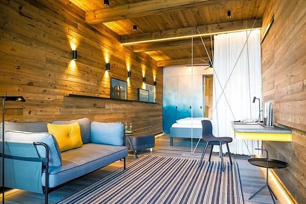 Un intérieur moderne avec un plafond en bois, un canapé avec des coussins, un tapis à rayures et un bureau avec une chaise.