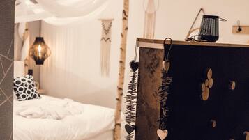 A bedroom with a bed, a bedside lamp, and a wall with hanging decorations.