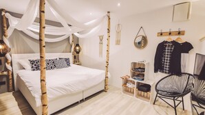 Une chambre à coucher avec un lit à baldaquin, une lampe de chevet, un miroir, un portant à vêtements, une télévision et une chaise.