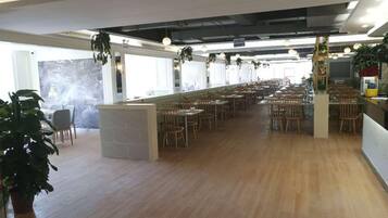 Un comedor interior amplio con suelo de madera, varias mesas y sillas.