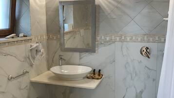 A bathroom with a white sink, mirror, and shower.