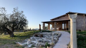 A building with a stone facade, a pathway leading to the entrance, and a large tree in the foreground. - Resort Fonte Vulci (Canino)