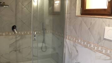 Kylpyhuone, jossa on lasiseinällä varustettu suihku, pesuallas ja wc.