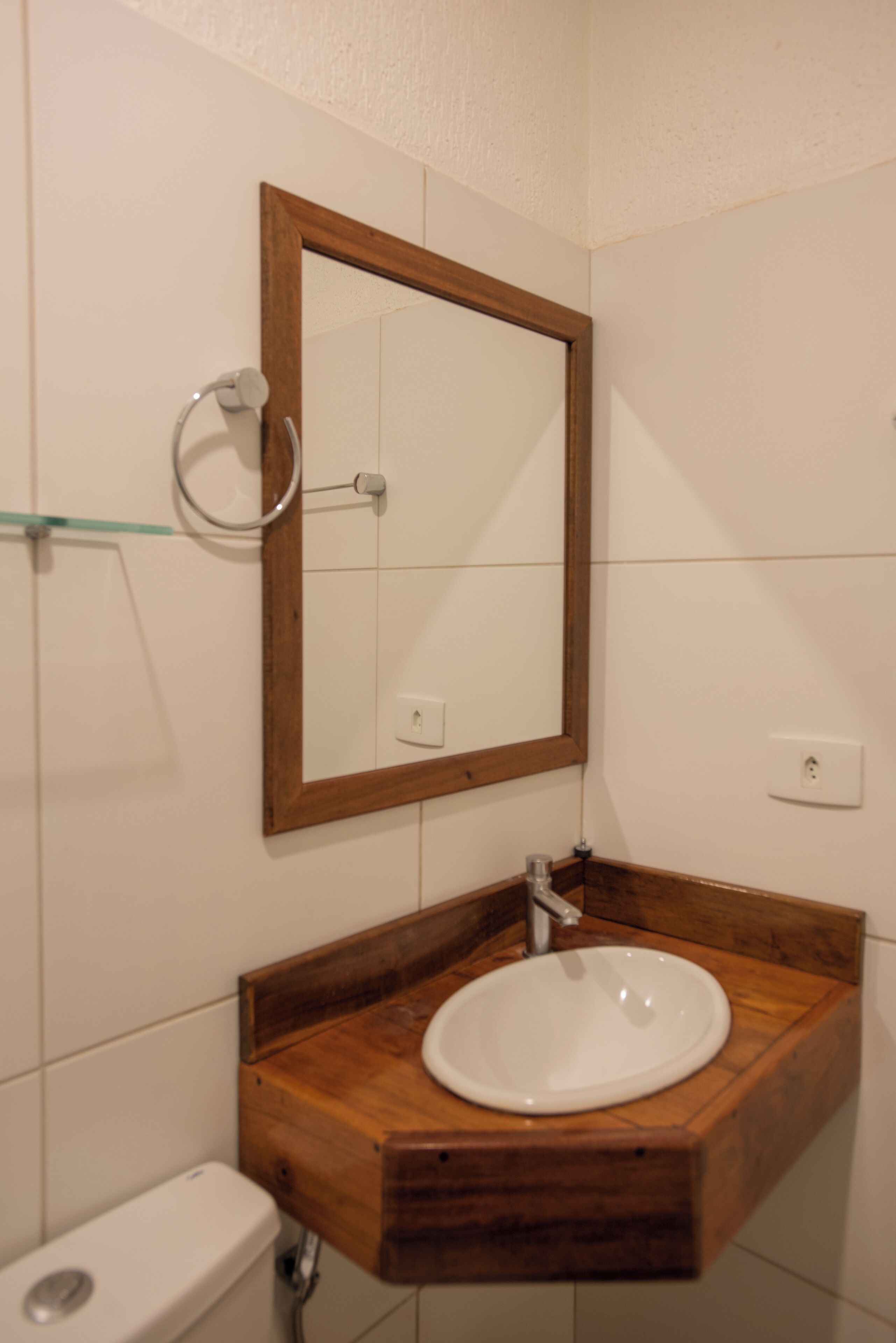 A bathroom with a wooden vanity, a white sink, and a mirror with a wooden frame.