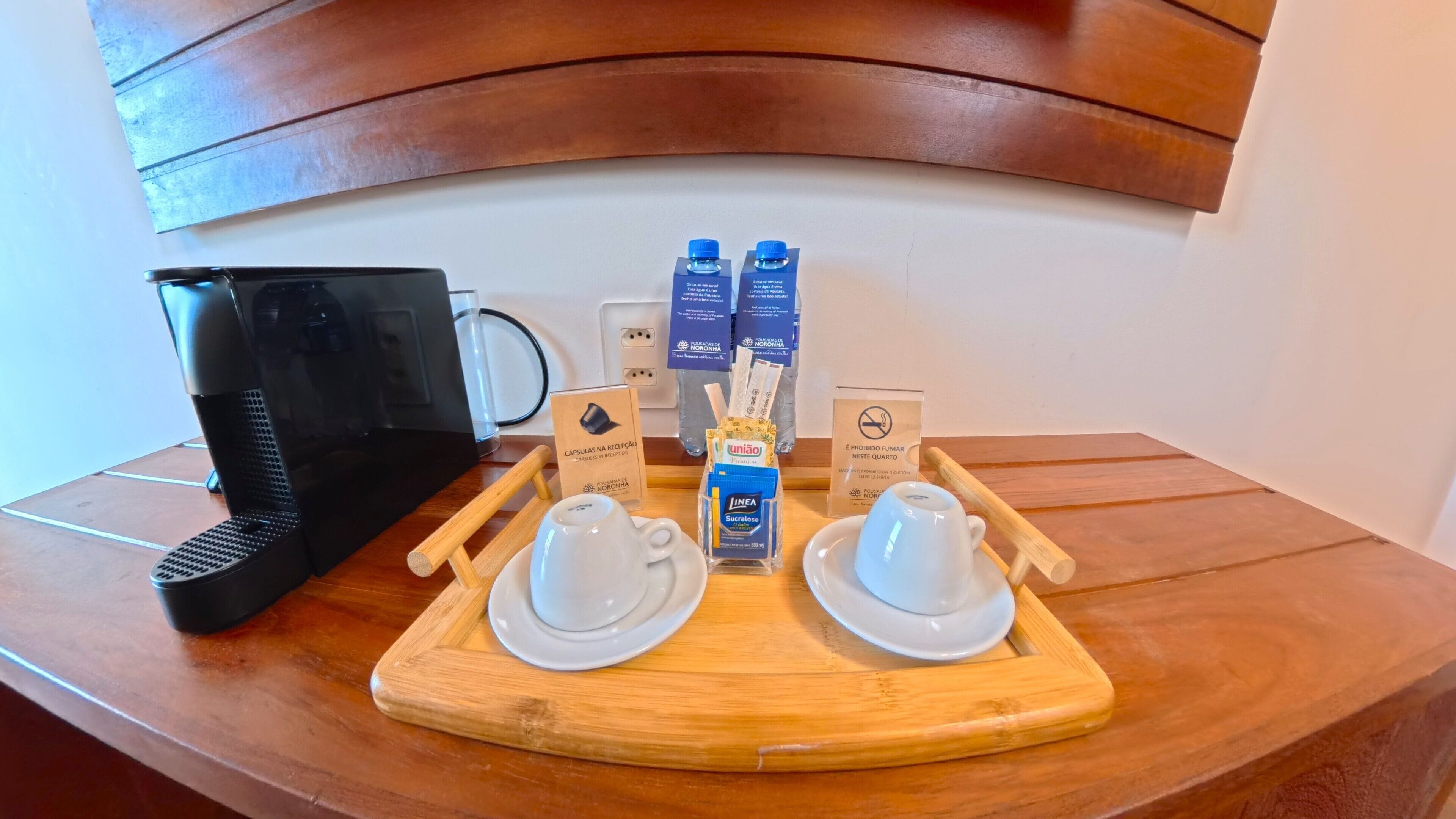 A breakfast setup with a coffee machine, two cups, a tray with condiments, and a sign indicating no smoking.