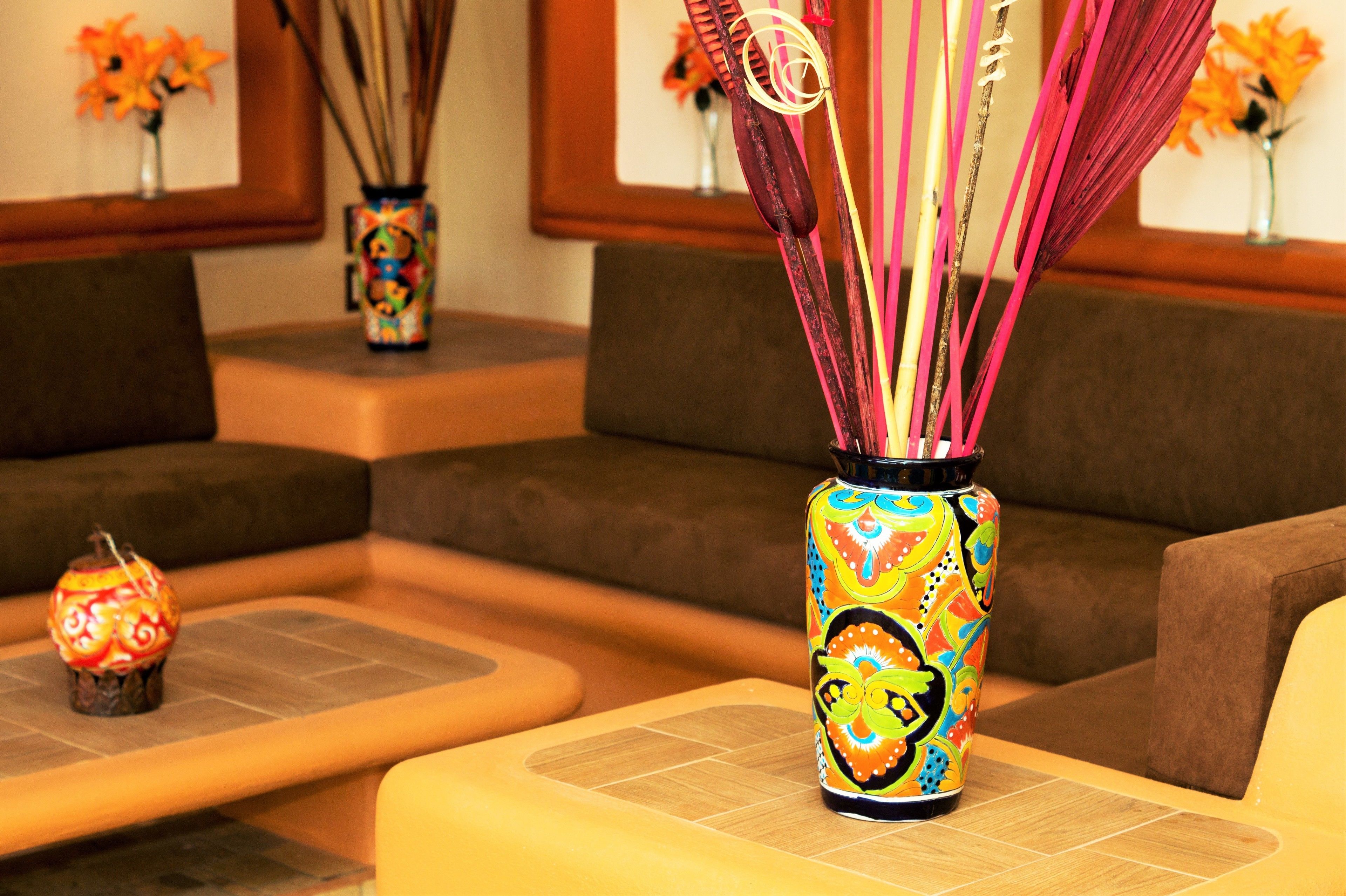 Una habitación con sofá, una mesita pequeña y un florero colorido con ramitas decorativas.