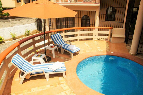 A pool area with lounge chairs and an umbrella. - Casa Cerca del Mar (Zihuatanejo)