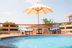 A poolside area with two lounge chairs and a large umbrella. - Casa Cerca del Mar (Zihuatanejo)