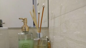 A bathroom with a white bathtub, a green bottle of soap, and two perfume bottles with reed sticks. - Habitat Tenente Silveira 600 AP 1208 (Florianópolis)