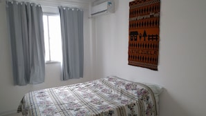 A bedroom with a bed, a window with curtains, an air conditioning unit, and a wall hanging. - Habitat Tenente Silveira 600 AP 1208 (Florianópolis)