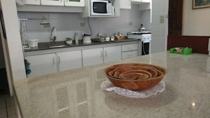 A kitchen with white cabinets, a microwave, a stove, and a sink. - Habitat Villa Florida Praia Ingleses (Florianópolis)
