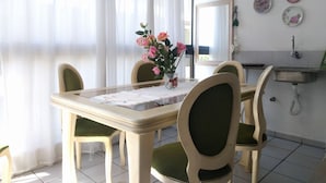 A dining area with a table and chairs, a vase with flowers, and a mirror on the wall. - Habitat Villa Florida Praia Ingleses (Florianópolis)