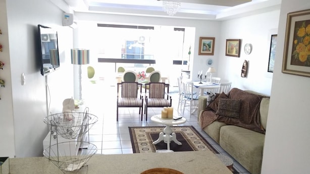 A living room with a sofa, chairs, a coffee table, and a dining area with a table and chairs. - Habitat Villa Florida Praia Ingleses (Florianópolis)