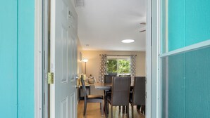 A dining area with a table and chairs, a ceiling light, and a window with curtains. - Great Tybee Stay with Heated Pool Access (Tybee Island)