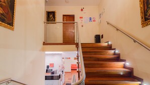 Eine Holztreppe mit Metallgeländer, ein Empfangstresen und eine Tür mit der Aufschrift '302' in der Hotelhalle.