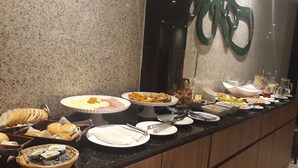 Noutopöytä, jossa on tarjolla erilaisia ruokia ja ruokailuvälineitä.