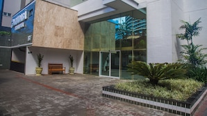 A modern building with a glass entrance, a wooden bench, and potted plants. - Aquidabã Praia Hotel (Fortaleza)