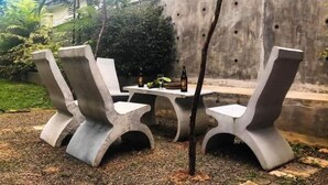 An outdoor seating area with two concrete chairs and a small table, surrounded by a concrete wall and greenery. - Villa Lagoonedge (Dodanduwa)