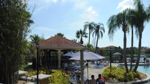 A resort pool area with lounge chairs, a gazebo, and palm trees.