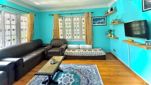 Un salón con sofá, sillón, mesa de centro, alfombra estampada, televisor y objetos decorativos.