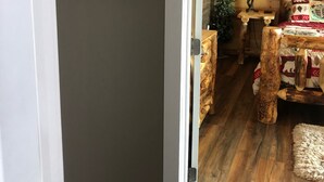 Un interior rústico con una puerta de madera, un cartel que dice “Te quiero hasta la luna y de regreso”, y un rincón acogedor con una mesa y sillas de madera.