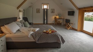 Une chambre avec un grand lit, un bureau et une chaise. Il y a une fenêtre donnant sur des arbres.