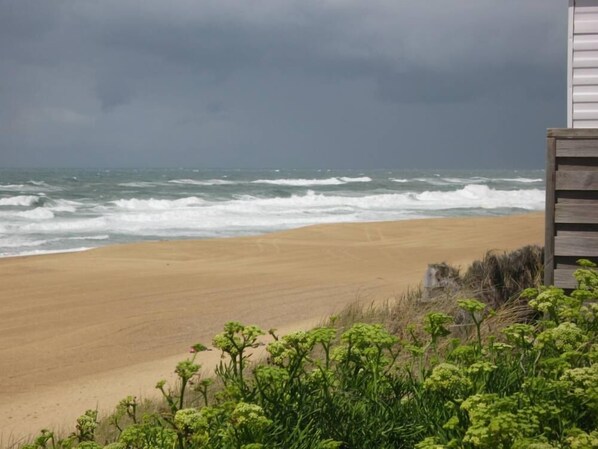 A beach with waves, a sandy shore, and a building with a wooden facade. - Cosy T3, 2bedroom, pool terrace near the sea  (Ondres)