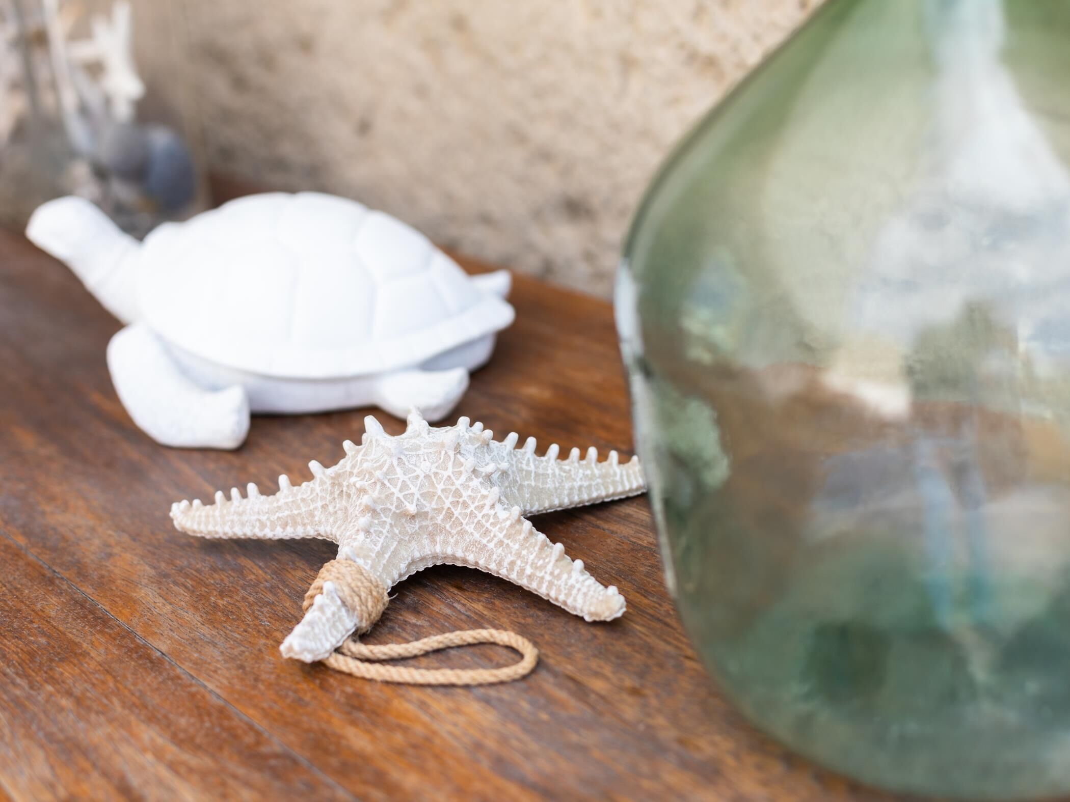 Una superficie de madera con un adorno de estrella de mar y una figurita de tortuga blanca.