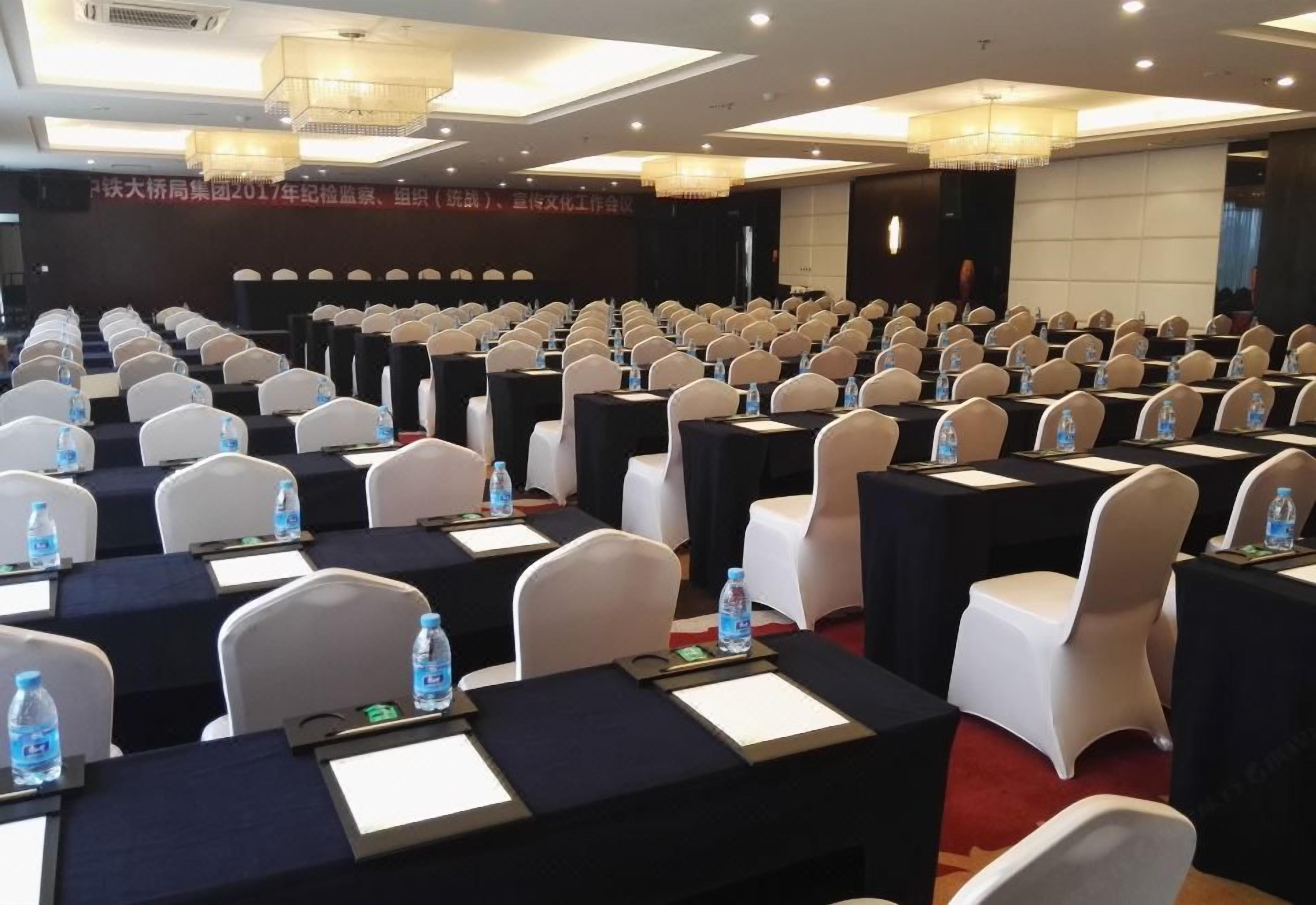 A conference room with rows of tables and chairs, equipped with nameplates and water bottles.