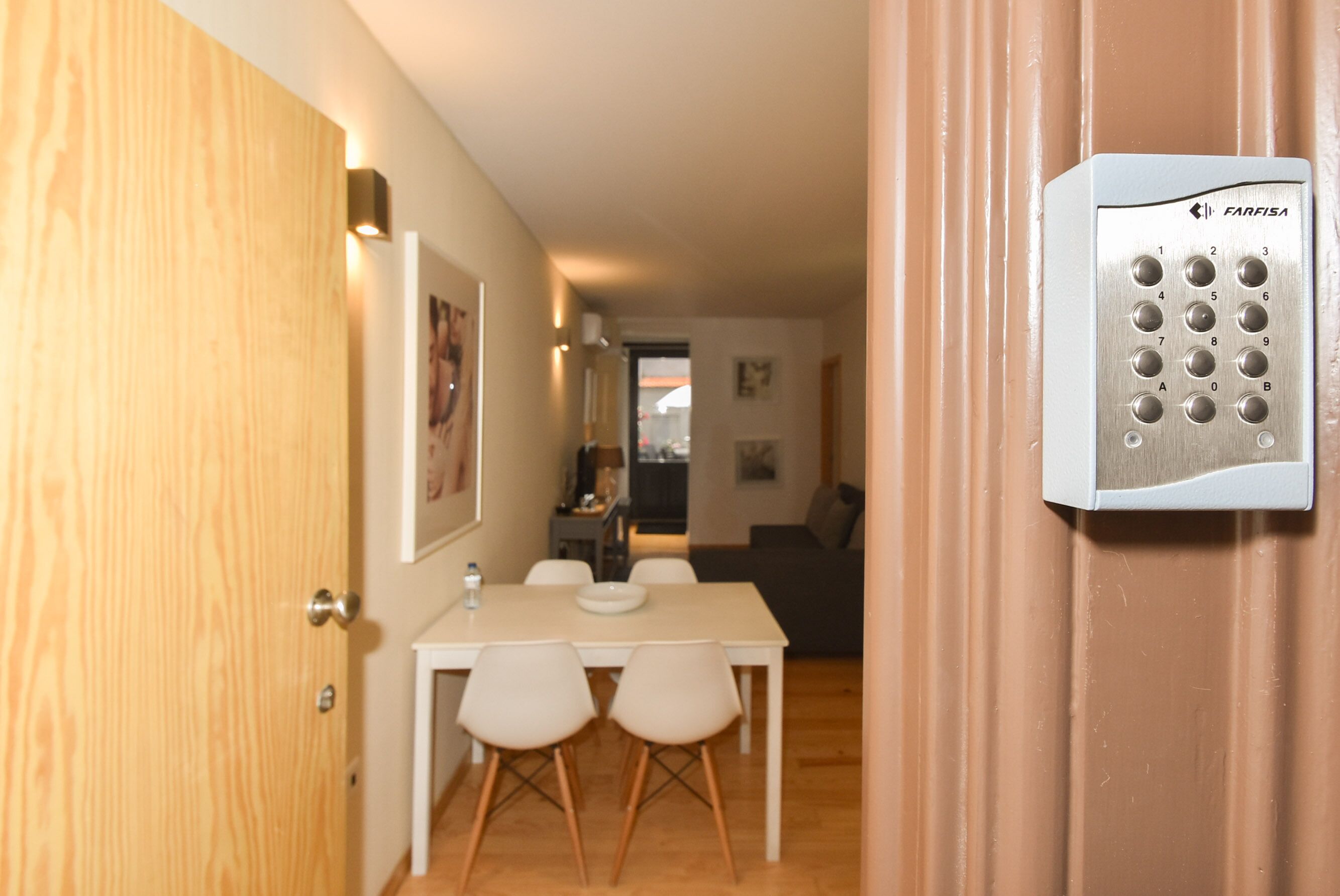 A hotel room with a dining area, a wall-mounted elevator control panel, and a wooden door.