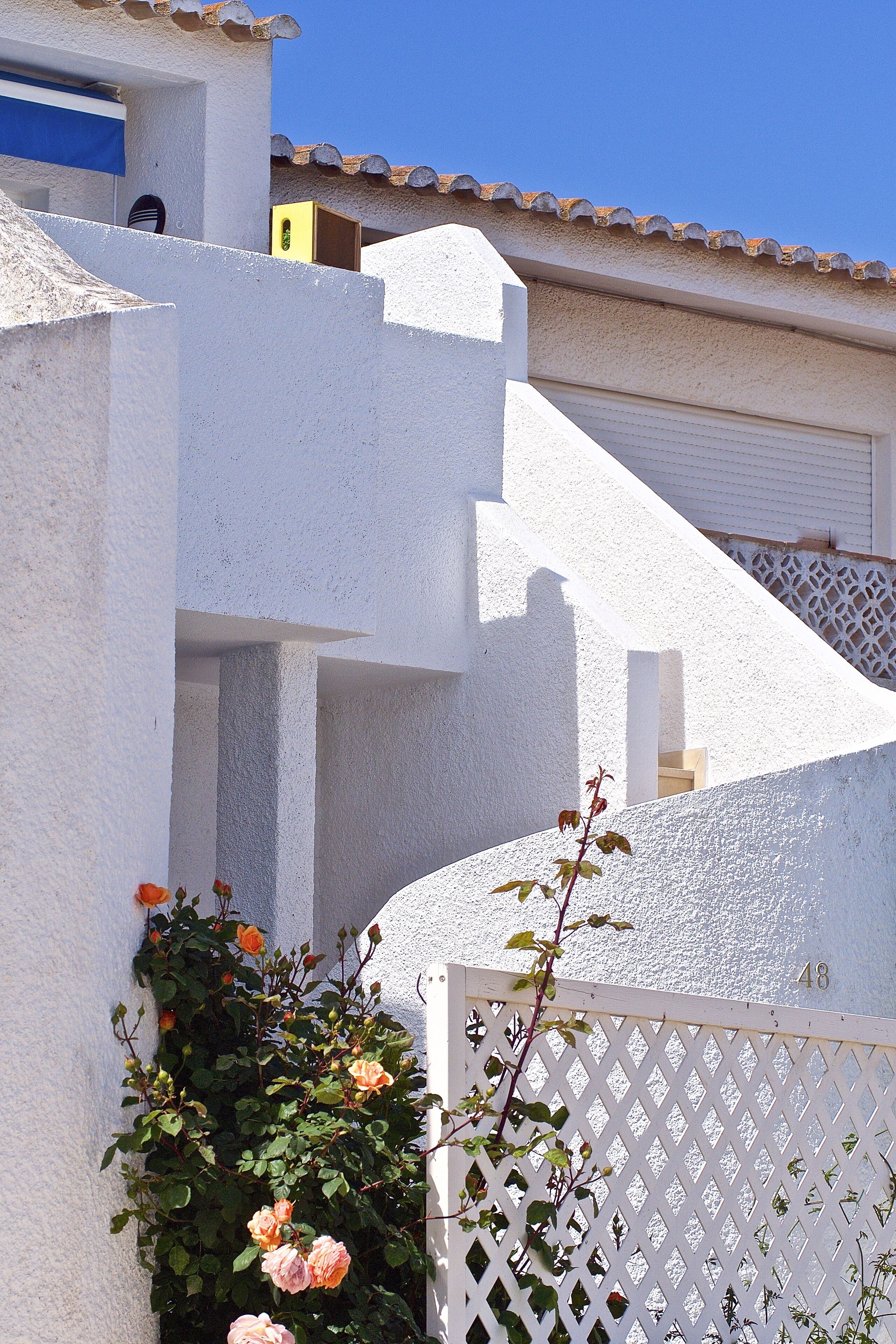 A white building with a sloped roof and a white fence.