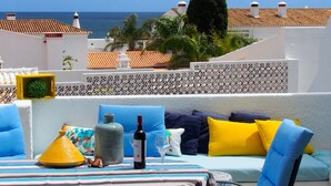 Una terraza con una mesa lista para cenar, que incluye una botella de vino y una copa.