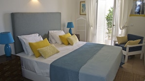 Un dormitorio ordenado con una cama grande, lámparas de noche y una silla.