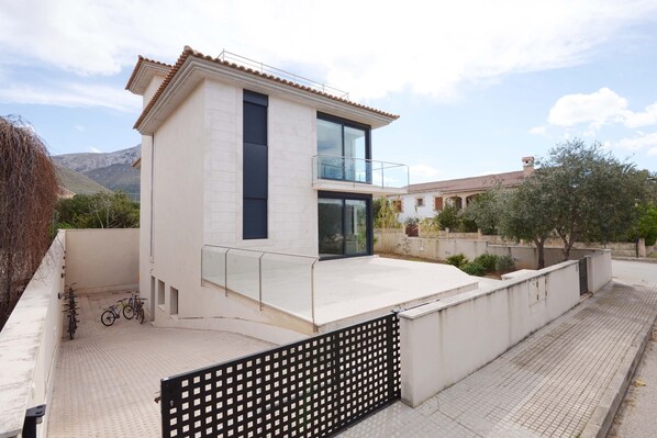 A modern two-story building with a balcony, a paved terrace, and a black metal fence. - House special for families and friends to 100 mt. of the sea. (Colonia de Sant Pere)