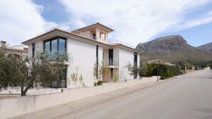 A modern two-story house with a balcony, large windows, and a mountain backdrop. - House special for families and friends to 100 mt. of the sea. (Colonia de Sant Pere)