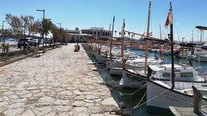 Un port de plaisance avec des bateaux amarrés, un chemin pavé et un bâtiment en arrière-plan.