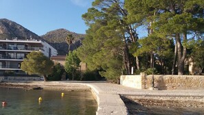 Une propriété située au bord de l’eau, dotée d’un mur en pierre, d’une piscine et d’un bâtiment avec des balcons.