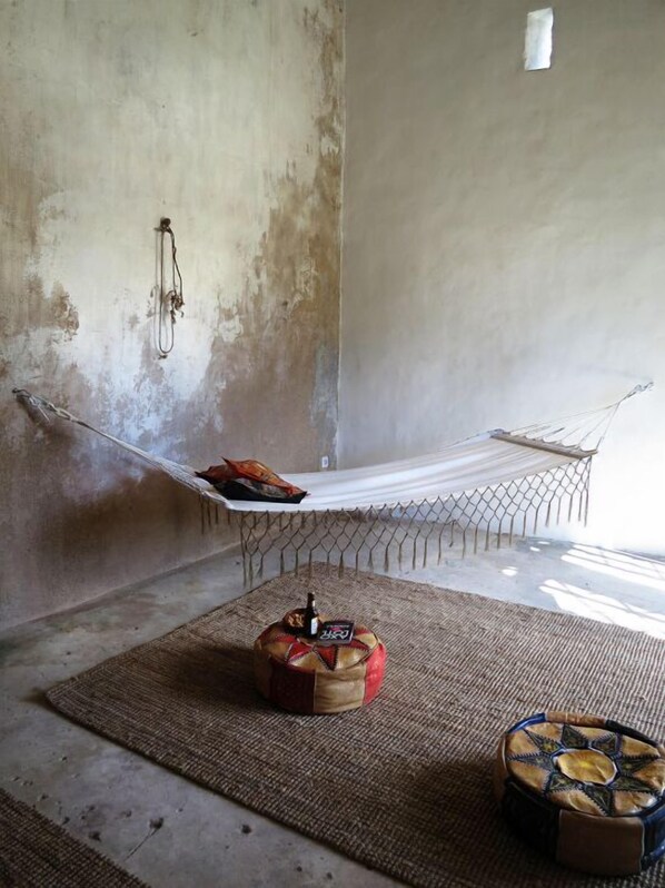 Ein Zimmer mit einer Hängematte, einem kleinen Teppich und einem dekorativen Gegenstand auf dem Boden.