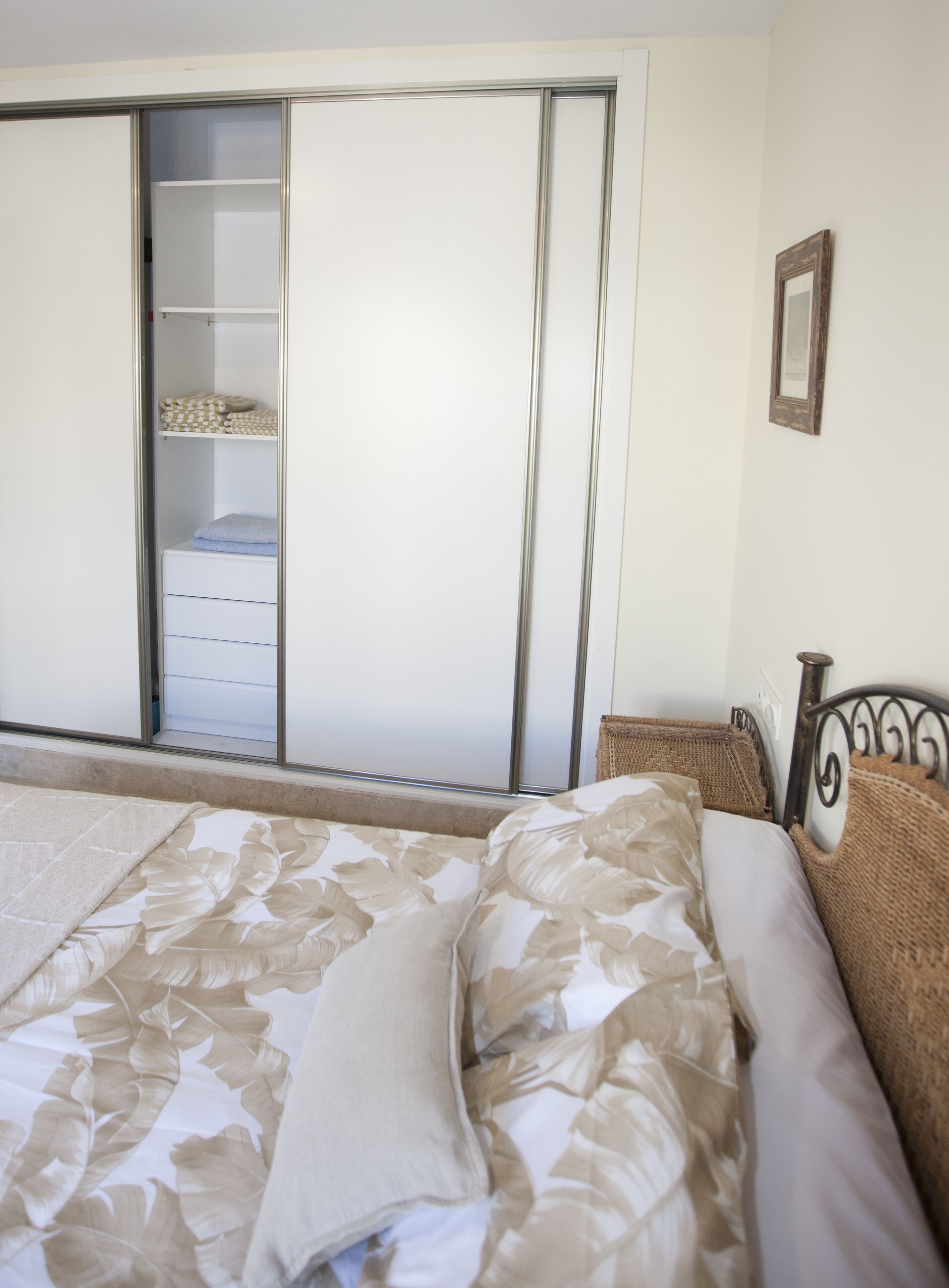 A bedroom with a bed, a wardrobe, and a small bedside table.