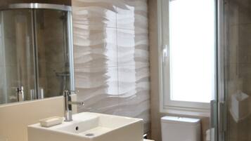 Een douche, handdoeken, shampoo, toiletpapier